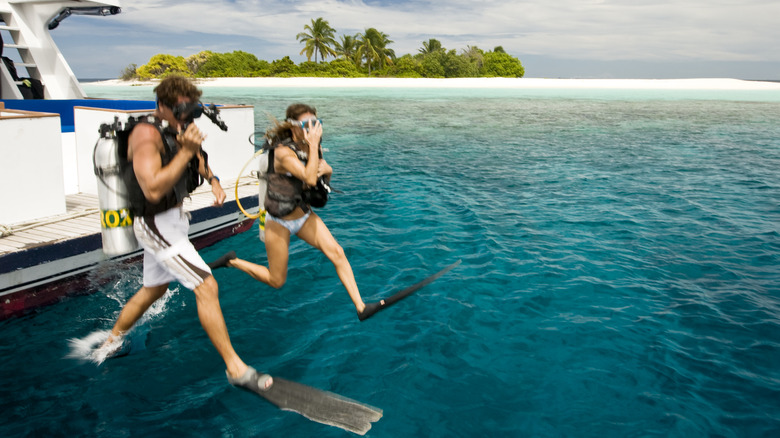 Couple jumping into the water for diving in the Maldives