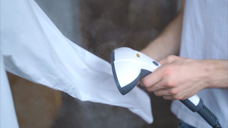 Closeup of man steaming a white shirt