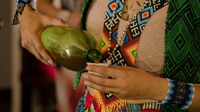 person pouring ayahuasca into cup