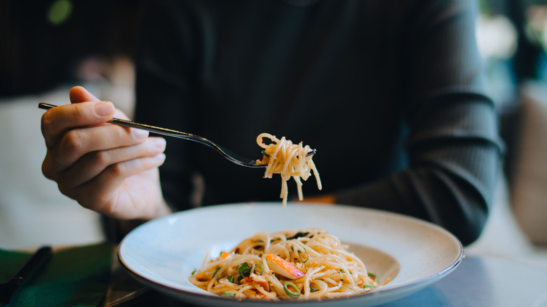 Hand picking up pasta with a fork