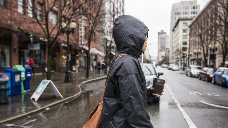 Woman in raincoat walking across a wet Seattle street