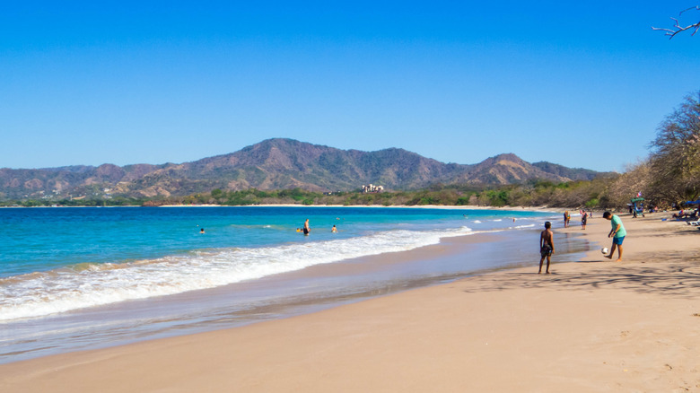 Beachgoers play in the waves and sand in Tamarindo