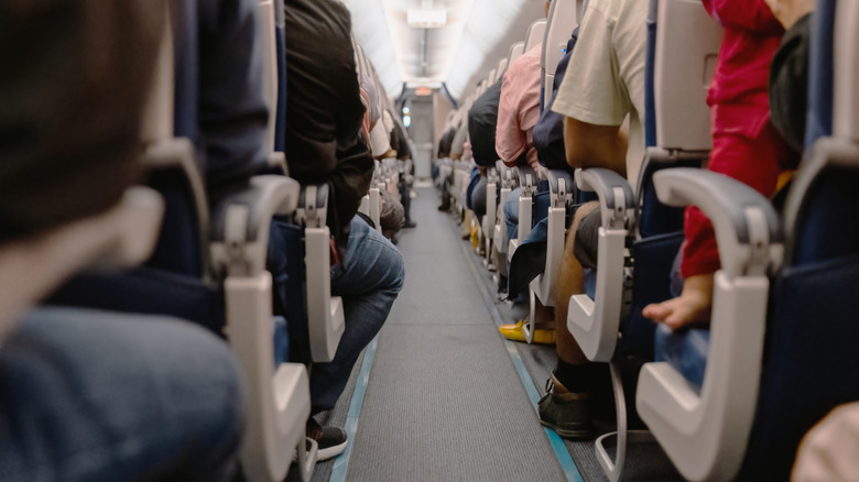 Airplane aisle with people seated