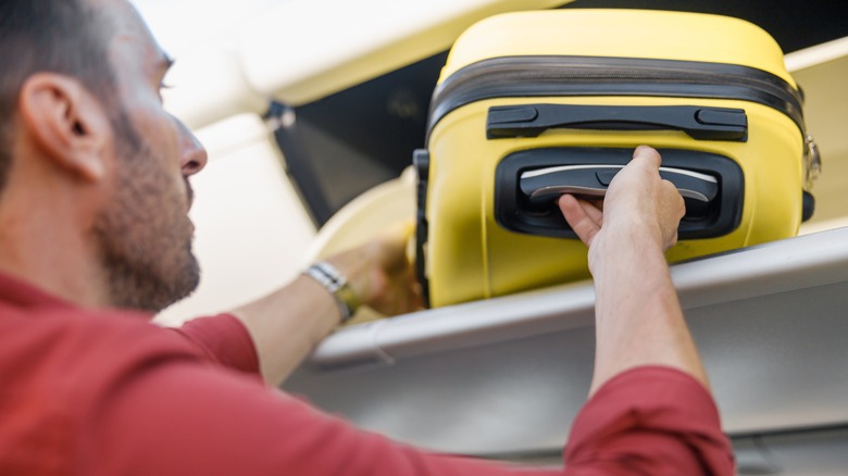 man pulling suitcase from bin