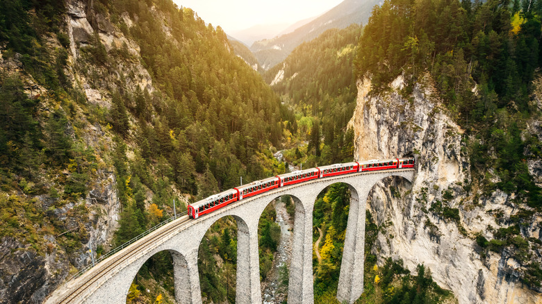 red train travels through mountains