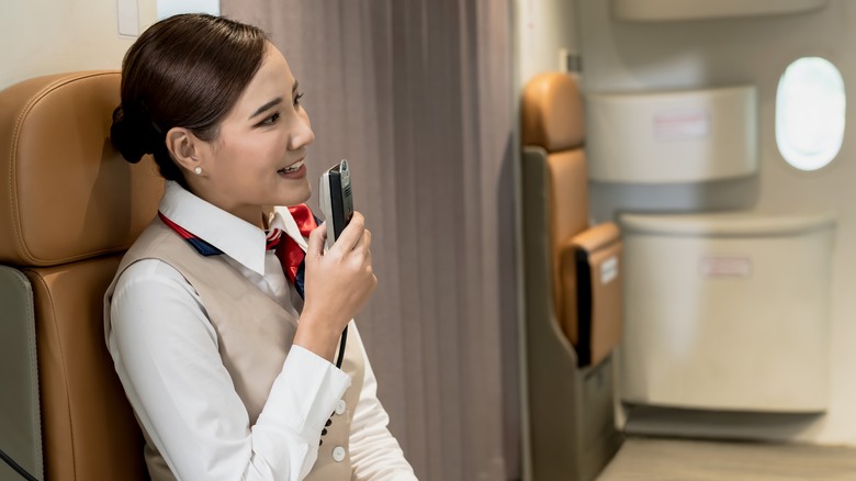 flight attendant sitting making announcement