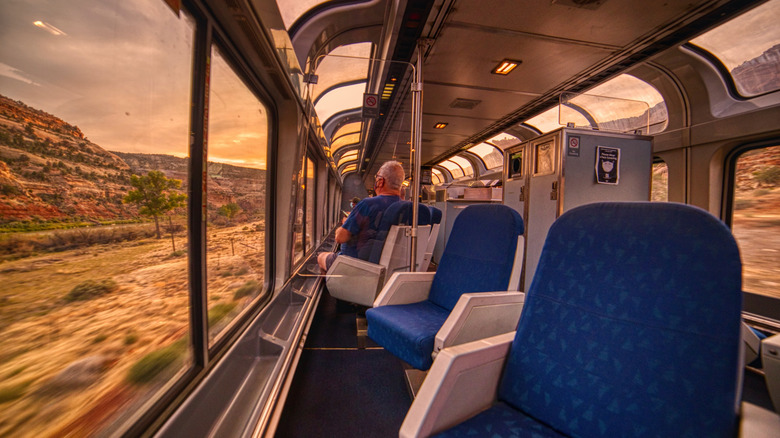 A passenger looks through wide windows in a southwestern Amtrak train