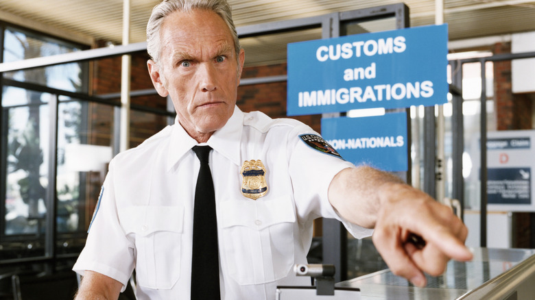 A security guard points intensely toward the camera