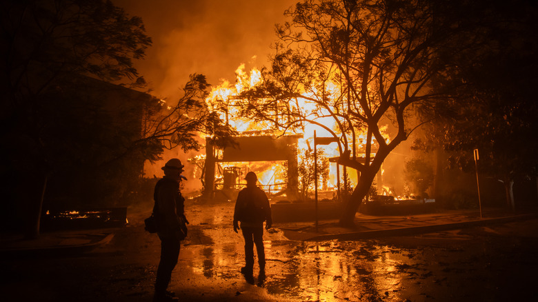 Firefighters monitor a burning house in Los Angeles