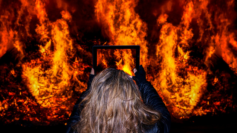 A woman snaps a picture of a massive fire