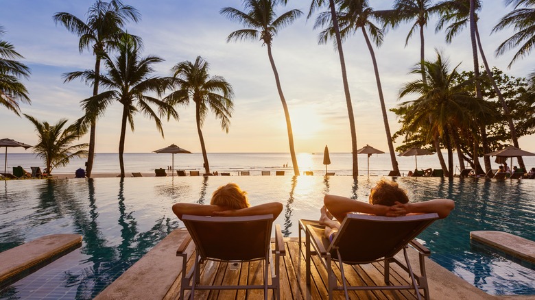 Couple relaxing by water with palm trees