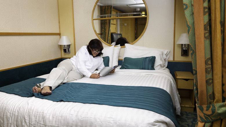 Woman reading in bed inside a cruise ship