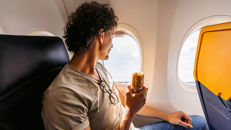 Man holding sandwich on plane