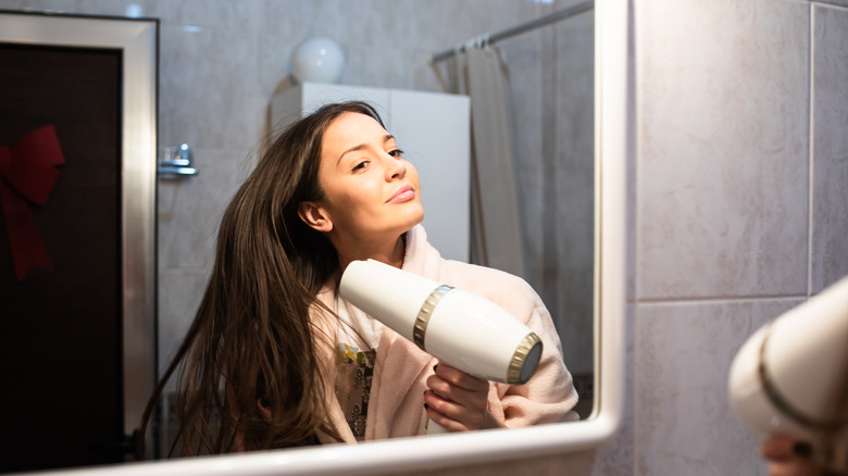 Woman blow drying hair in bathroom