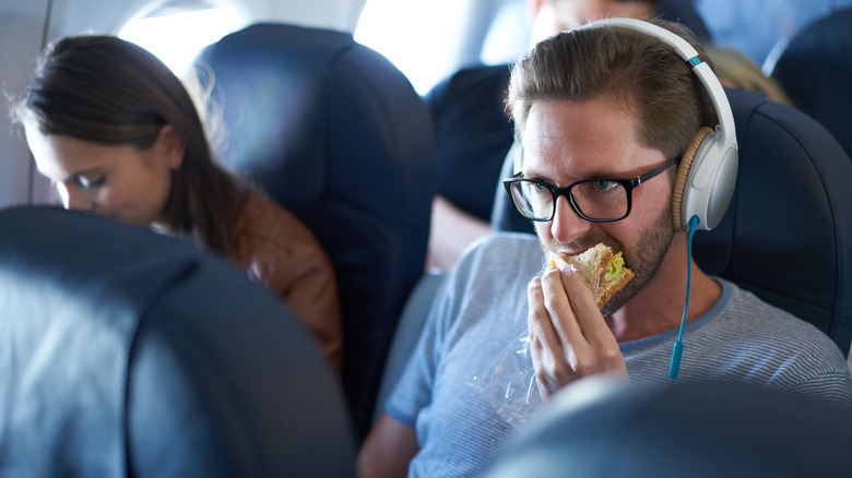 man eating sandwich on plane