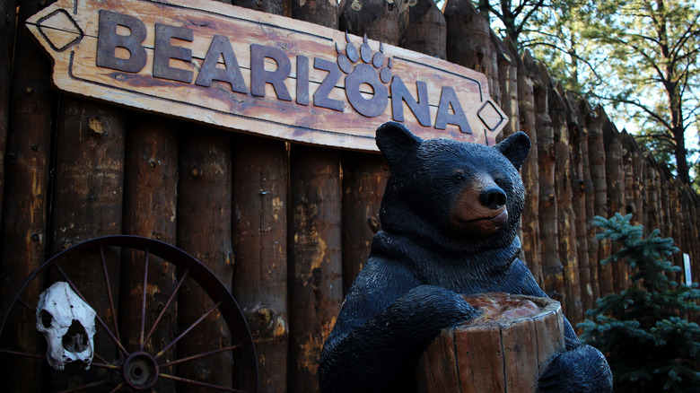 A bear sculpture stands in front of the Bearizona sign.