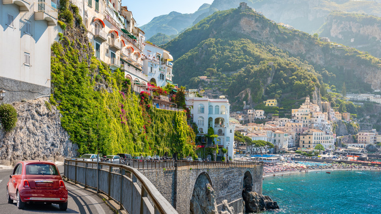 Red car driving along road on Amalfi Coast with scenic views