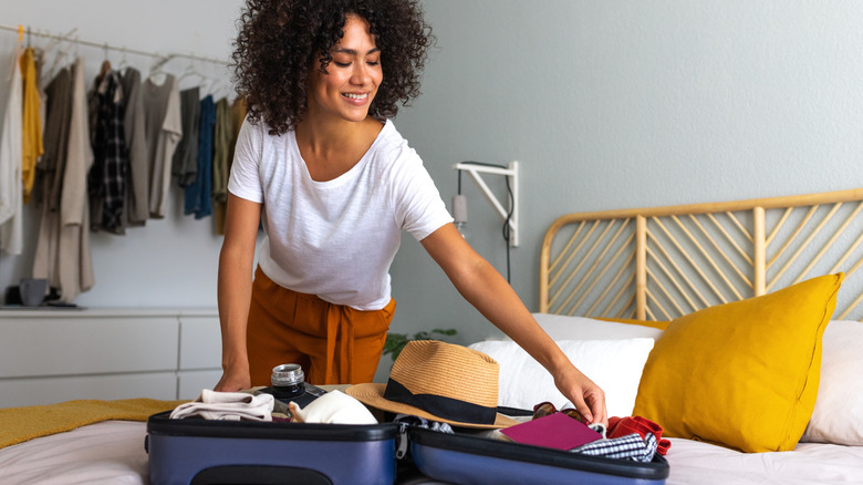 Traveler packing suitcase on a bed