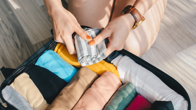 Traveler folding clothes into suitcase