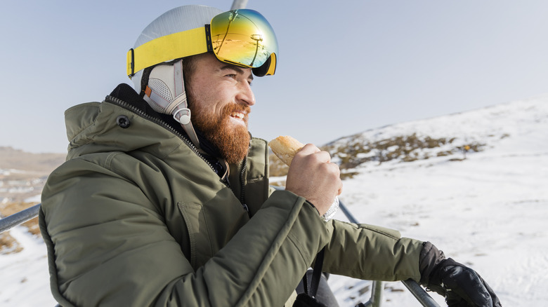 Man eating snack on a snowy mountain