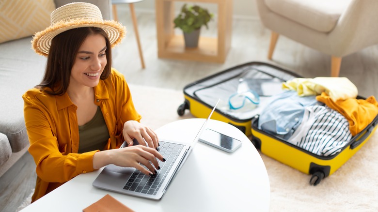 Woman on her laptop next to a suitcase