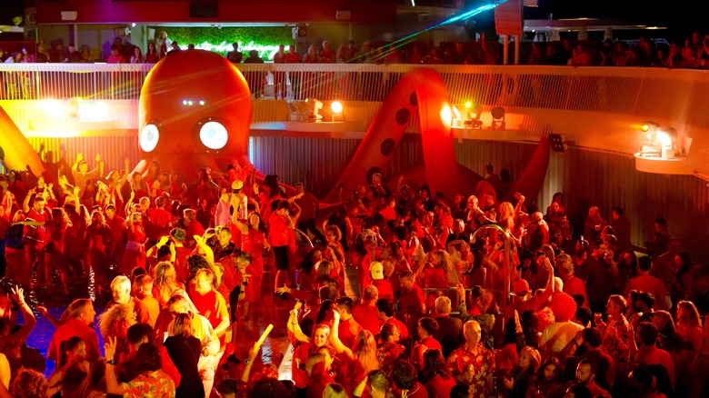 A throbbing mass of people enjoys an evening party on a cruise ship