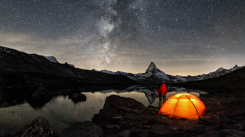 camper stargazing near tent