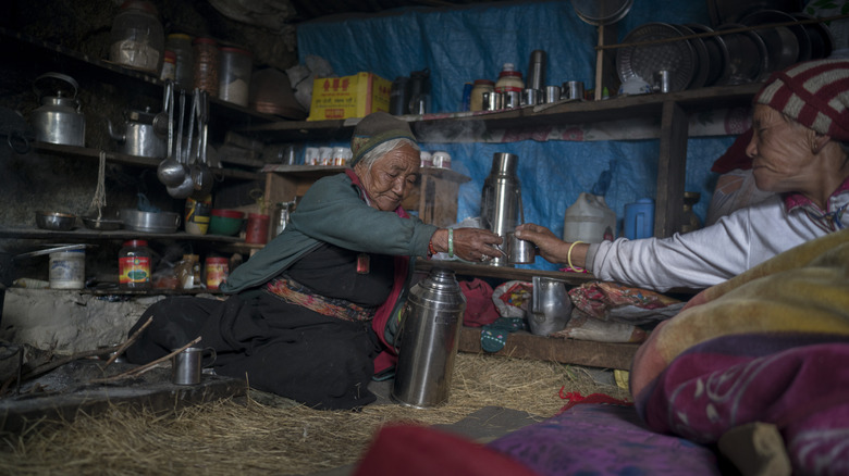 Nepalese tea house Nepalese women hand tea to one another