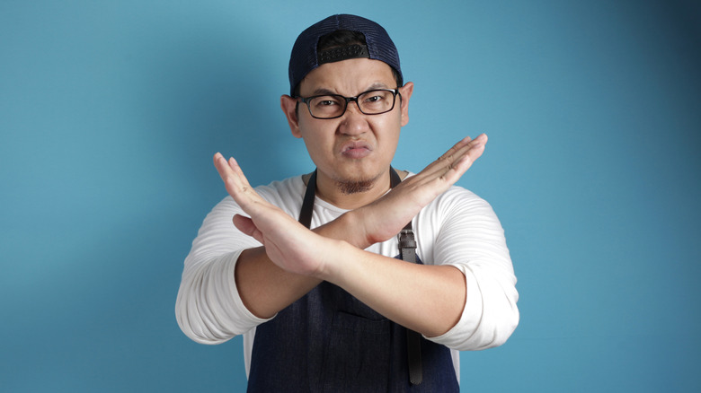 An angry Asian chef crosses his arms