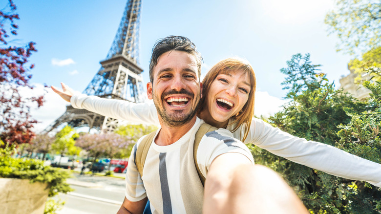 Man and woman take a picture in front of the Eiffel Tower