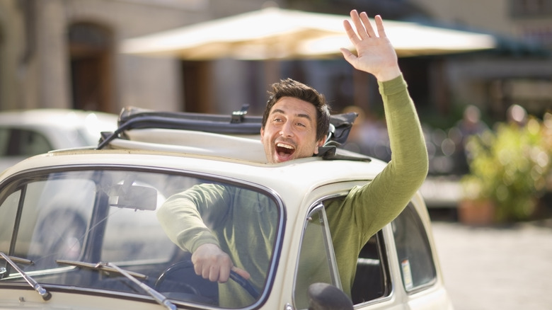 Man driving car and waving wildly