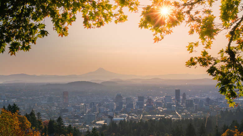 The sun gleams over the Portland, Oregon skyline as Mount Hood rises in the background