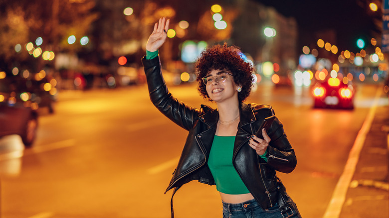 Woman hailing cab at night