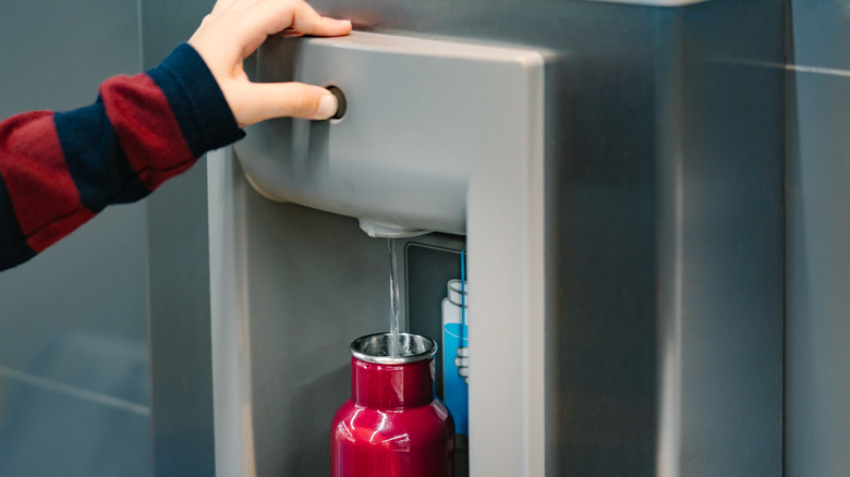 traveler refilling reusable water bottle