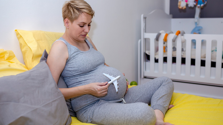 Pregnant person with toy plane by belly
