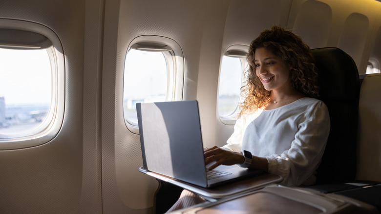 A woman uses a laptop on a flight.