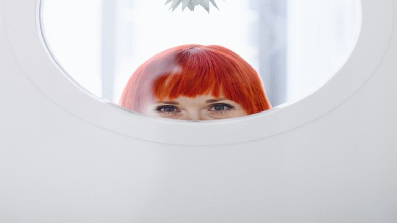 An upside-down pineapple peeks out from the rim of a porthole