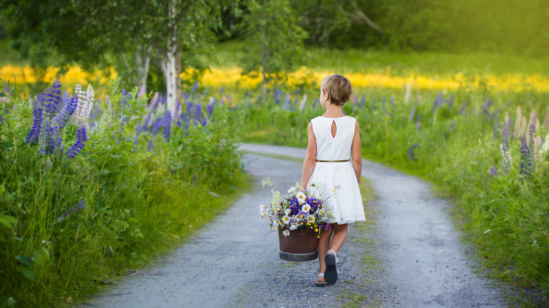girl walking with bucket of flowers