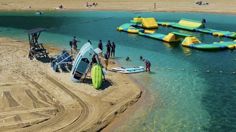 Beachgoers with paddleboards and aquatic toys