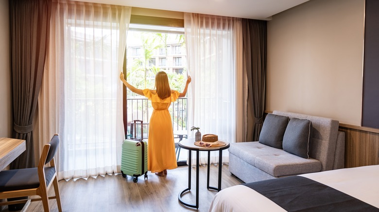 woman opening hotel room cutrains