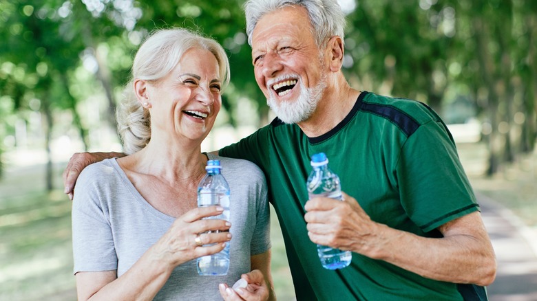 Senior couple holding plastic water bottles
