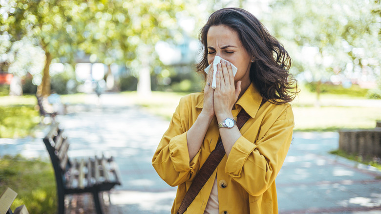 Woman blows her nose in a public park