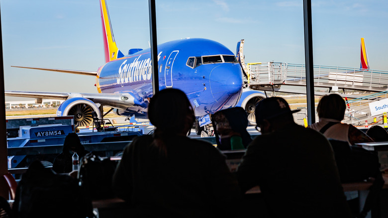 People waiting at airport with Southwest plane in background