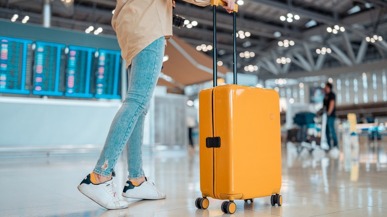 person pushing suitcase through airport