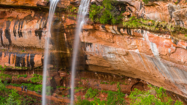 hikers under enormous waterfall