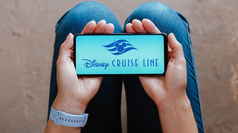 Hands holding phone displaying Disney Cruise Line