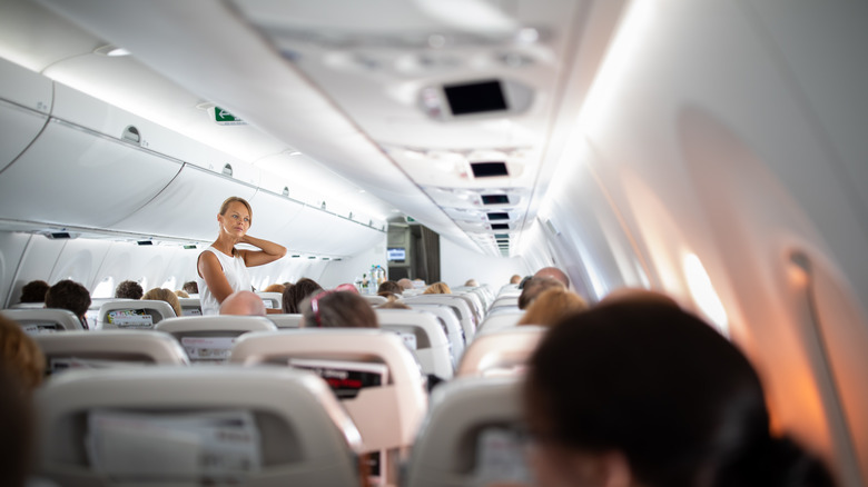 Woman standing at airplane aisle