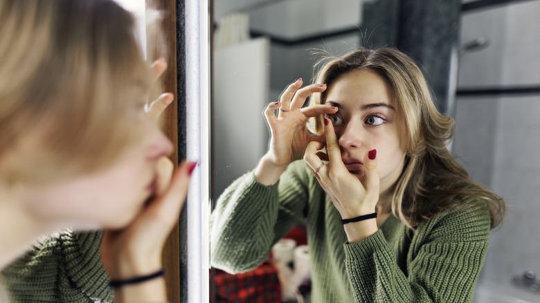 Girl putting on contact lenses
