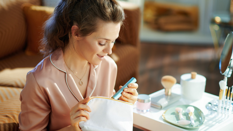 woman putting mascara in bag