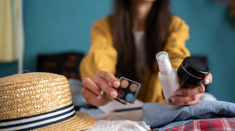 woman packing cosmetics in suitcase